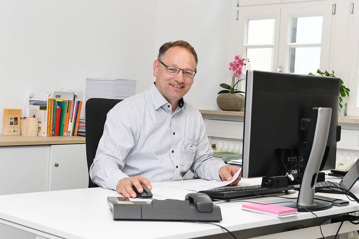 Quelle: Erzbischöfliches Seelsorgeamt Freiburg - Bildungshäuser und Familienferienstätten Bild von der Hausleitung, Ulrich Baudenbacher am Schreibtisch