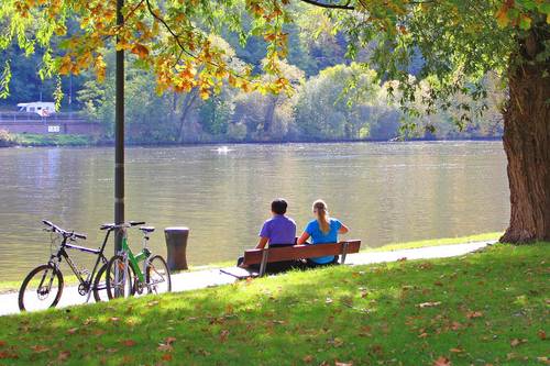 Radfahrer auf einer Bank sitzend an einem Fluss
